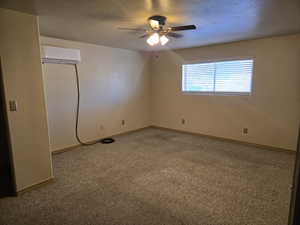 Empty room featuring carpet flooring, a ceiling fan, and a textured ceiling
