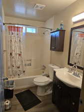 Bathroom with vanity, shower / tub combo with curtain, a textured ceiling, and dark wood-style flooring
