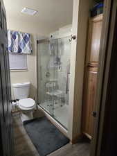 Full bath featuring a textured ceiling, dark wood-style flooring, and a shower stall