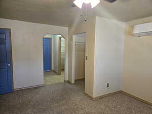 Empty room with arched walkways, ceiling fan, light colored carpet, and a textured ceiling