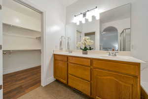 Full bathroom with double vanity, light tile patterned flooring, and a spacious closet
