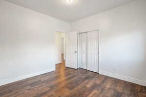 Unfurnished bedroom featuring a closet and dark wood finished floors