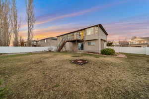 Back of property at dusk featuring a fenced backyard and a wooden deck