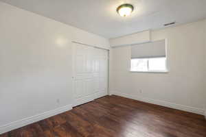Unfurnished bedroom with a closet and dark wood-style floors