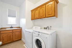 Washroom with washing machine and clothes dryer, cabinet space, and light tile patterned flooring