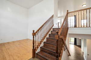 Stairs featuring wood finished floors and a towering ceiling