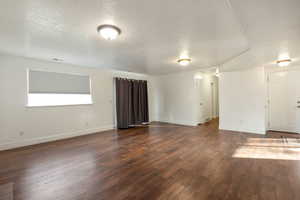 Unfurnished living room with a textured ceiling and dark wood-style floors
