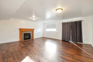 Unfurnished living room with a fireplace, dark wood-style floors, and a textured ceiling