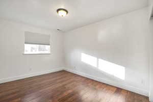Empty room with baseboards and dark wood-style flooring