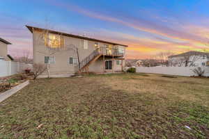 Back of house at dusk featuring a fenced backyard and a deck