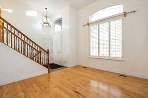 Foyer featuring light wood finished floors, a high ceiling, stairway, and a chandelier