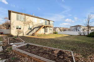 Back of house with a fenced backyard, a garden, stairway, and a deck