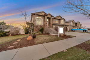 View of front facade with concrete driveway, stucco siding, a garage, and a front lawn