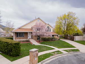 View of front facade with brick siding, a porch, and roof with shingles