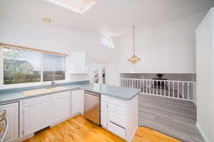 Kitchen featuring a peninsula, light wood-style flooring, white cabinets, pendant lighting, and vaulted ceiling