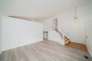 Unfurnished living room with suspended lighting and light wood finished floors