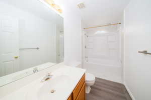 Full bath featuring vanity, washtub / shower combination, and dark wood-type flooring