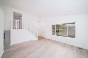 Unfurnished living room with stairs and light wood-type flooring