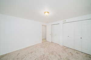 Unfurnished bedroom with multiple closets and carpet floors