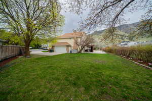 View of yard with a mountain view, a garage, concrete driveway, and a patio area