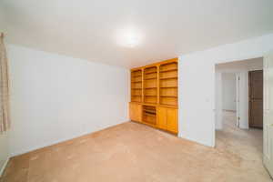 Empty room featuring built in shelves and light carpet