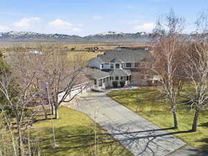 View of front facade with driveway, a chimney, a mountain view, a front lawn, and a patio