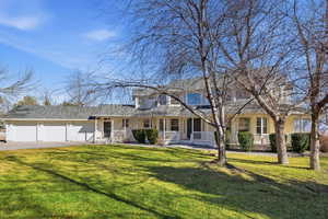View of front of property featuring a front lawn, covered porch, and asphalt driveway