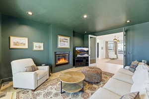Living room featuring a glass covered fireplace, wood finished floors, and recessed lighting