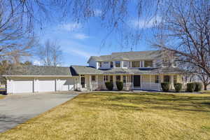 View of front of property featuring covered porch, a front lawn, concrete driveway, a garage, and roof with shingles