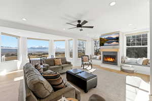 Living area featuring light wood-style floors, a glass covered fireplace, ceiling fan, and recessed lighting