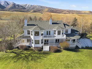 Rear view of house featuring a chimney, a lawn, roof with shingles, and a mountain view