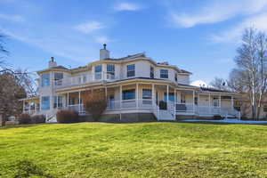 Victorian house with a chimney, a large porch, and a front yard