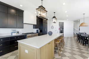 Dual tone kitchen featuring light flooring, a large island, two tone cabinetry, pendant lighting, and a breakfast bar