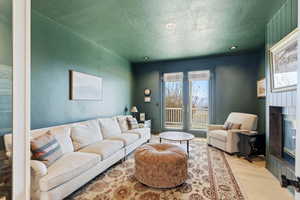 Living area featuring wood finished floors, a textured ceiling, a glass covered fireplace, and recessed lighting