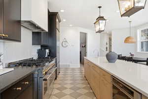Kitchen with double oven range, dark stone counters, decorative light fixtures, and light flooring