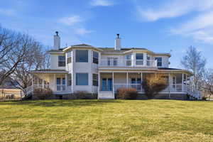 Back of house with a chimney, a large porch, and a lawn