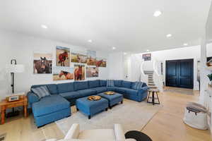 Living area with light wood-type flooring and recessed lighting