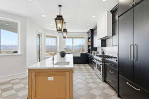 Kitchen featuring high end appliances, pendant lighting, light stone counters, a kitchen island with sink, and a mountain view
