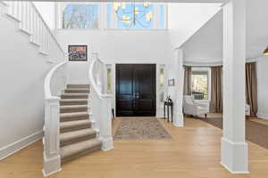 Entryway with light wood-style flooring, suspended lighting, and a high ceiling