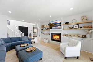 Living room featuring a glass covered fireplace, light wood-type flooring, built in shelves, and recessed lighting