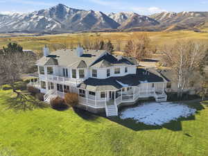 Back of property with a porch, a lawn, a chimney, and a mountain view