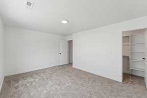 Unfurnished bedroom with a spacious closet and light colored carpet