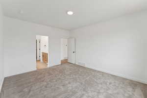 Unfurnished bedroom featuring light carpet and ensuite bathroom