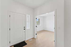 Foyer entrance with light wood finished floors and baseboards