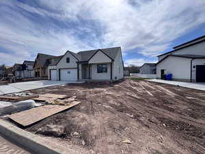 View of front of home with a residential view, concrete driveway, stucco siding, and an attached garage