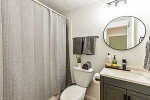 Bathroom with a textured wall, vanity, a shower with curtain, and a textured ceiling