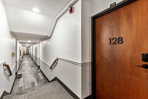 Hallway featuring a textured wall and baseboards