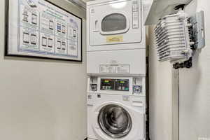 Shared laundry room with stacked washing machine and dryer and a textured wall
