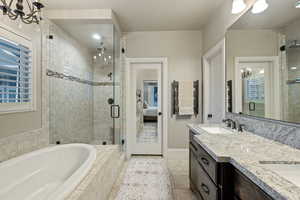 Bathroom featuring ensuite bath, double vanity, healthy amount of natural light, and a shower stall