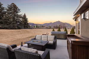 View of patio with a hot tub, a mountain view, and an outdoor living space with a fire pit